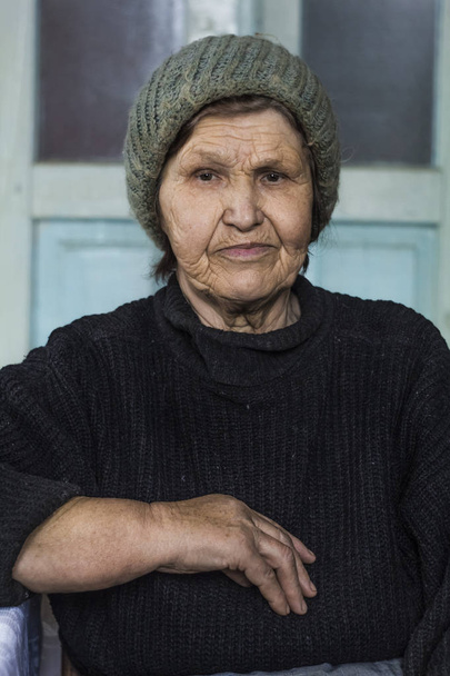 Portrait of an elderly woman. A thoughtful grandmother sits in a room. - Foto, immagini