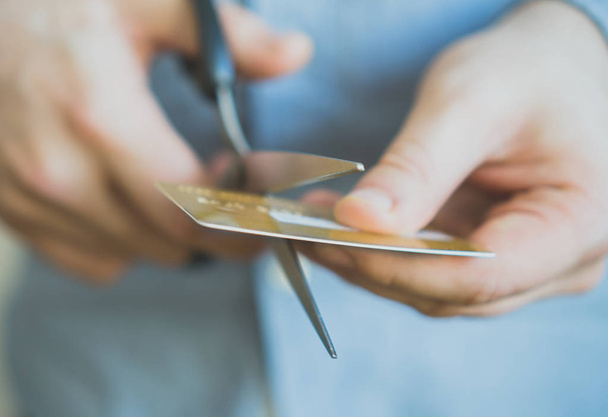 Man cutting gold credit card with scissors. - Foto, afbeelding