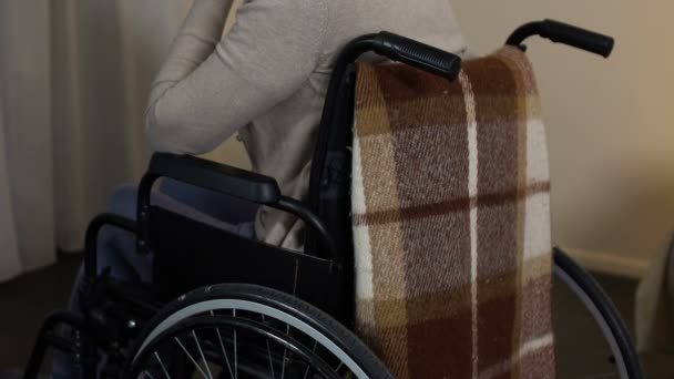 Masentunut vanha nainen pyörätuolissa katselee ikkunaa, tuntee yksinäisyyttä hoitokodissa
 - Materiaali, video