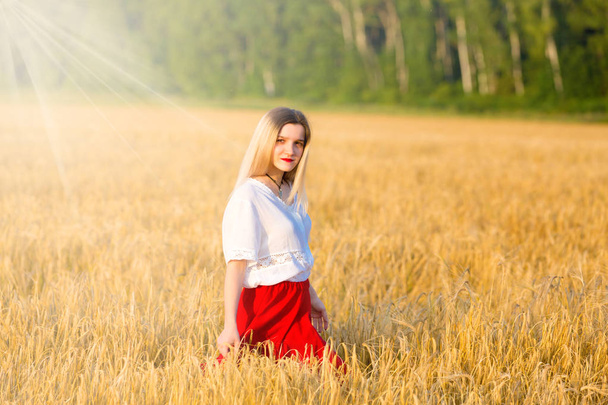 Прекрасна дівчина в традиційному костюмі гуляє на полі зернових
 - Фото, зображення
