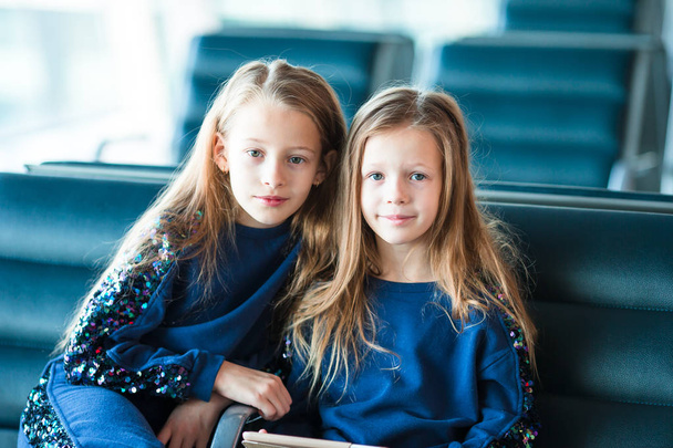 Pequenas garotas adoráveis no aeroporto à espera de embarque perto de uma grande janela
 - Foto, Imagem