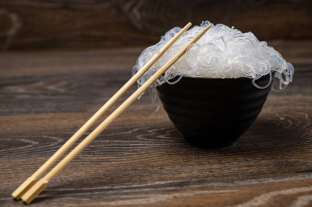 Rise noodles in black bowl on wooden background - Photo, Image