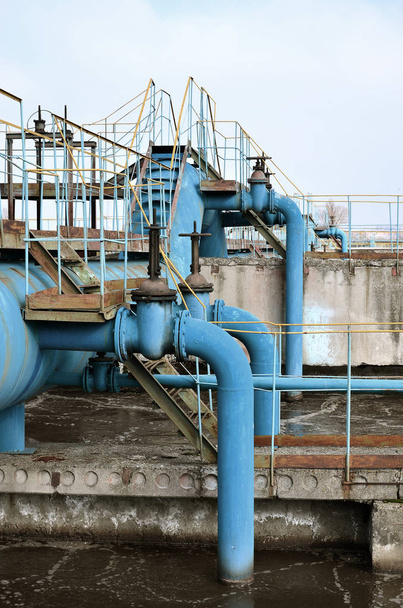 Teollisuustila, jossa on paljon putkia ja viestintää sinisen taivaan taustalla. vanha vedenpuhdistamo kaupungin vesihuoltoyrityksessä. Kharkov, Ukraina
 - Valokuva, kuva