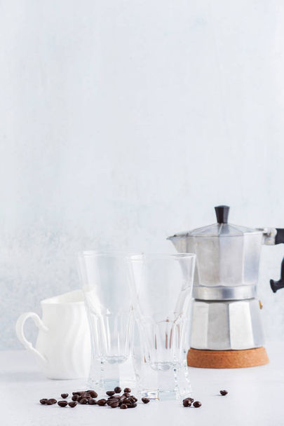 empty glasses and a milk jug with coffee beans and coffee maker  - Foto, Imagen