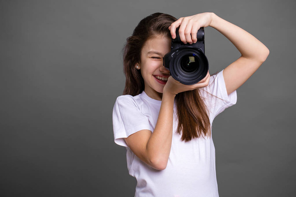 Cute brunette little girl holding an photo camera - Fotó, kép
