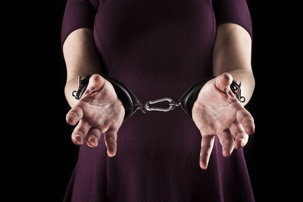 submissive woman wearing a purple dress in leather handcuffs on  - Foto, afbeelding