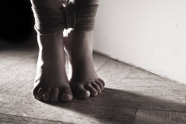 Detail suspendierte gebundene Füße unterwürfiges junges Mädchen auf einem schwarzen Bac - Foto, Bild