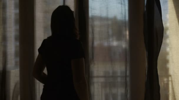 Mujer ensanchando cortinas dejando que los rayos brillantes de sol cálido de verano en la habitación
 - Metraje, vídeo
