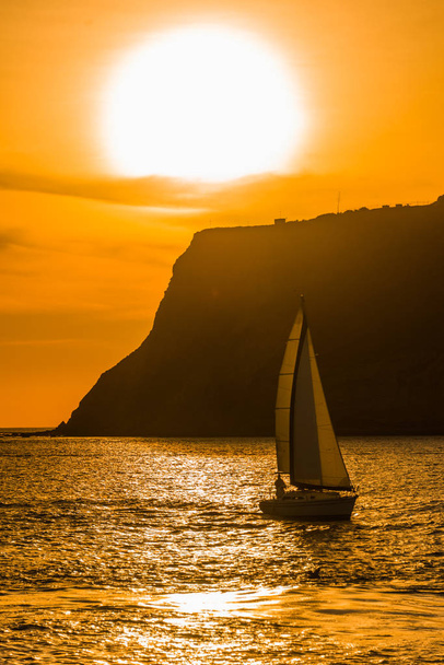 Vibrante puesta de sol del océano naranja con un velero
 - Foto, imagen