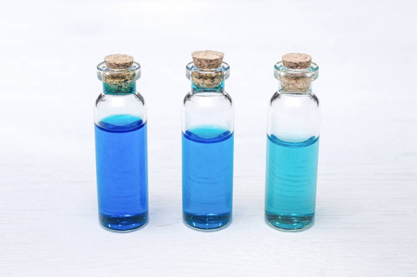 Blue essential oil tincture bottles of different transparency on white wooden background. Alternative medicine. Herbal medicine. Aroma therapy. - Photo, image