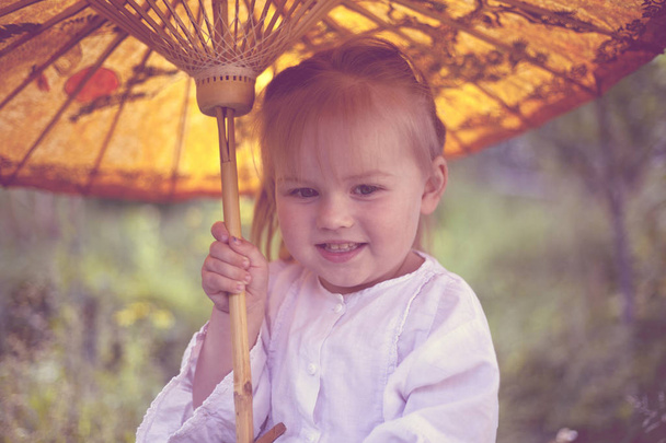 Όμορφη λευκή κοπέλα με χαμόγελο κάτω από μια ομπρέλα. - Φωτογραφία, εικόνα