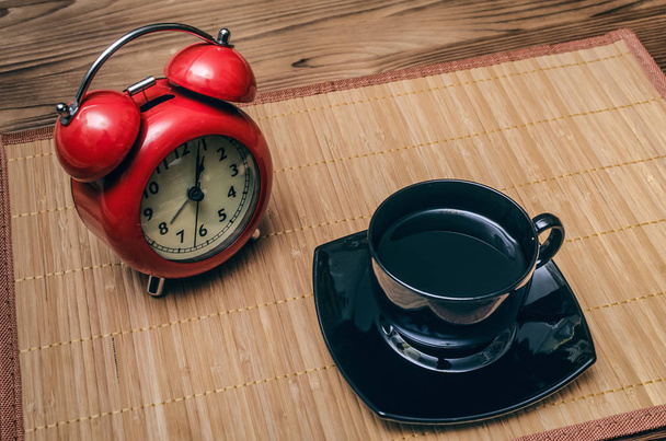 Red alarm clock and cup of black coffee on office desk table background. Coffee break concept. - Fotografie, Obrázek