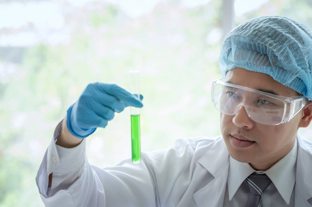 Junge männliche Wissenschaftlerin steht im Labor und macht medizinische Experimente - Foto, Bild