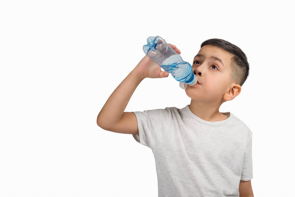 Το μικρό αγόρι πίνει νερό από ένα μικρό πλαστικό μπουκάλι για ένα whi - Φωτογραφία, εικόνα