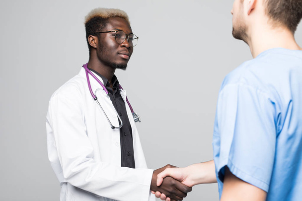 Medical handshake. Doctoral meeting. Two confident doctor and surgeon standing on gray and shake their hands. - Foto, Imagem