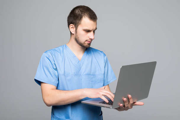 The doctor staring on the laptop isolated on gray background - Valokuva, kuva