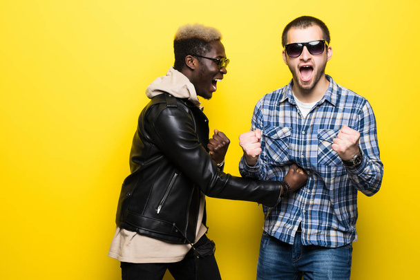 Young mixed raced friends fun fight on yellow background. - Foto, Bild