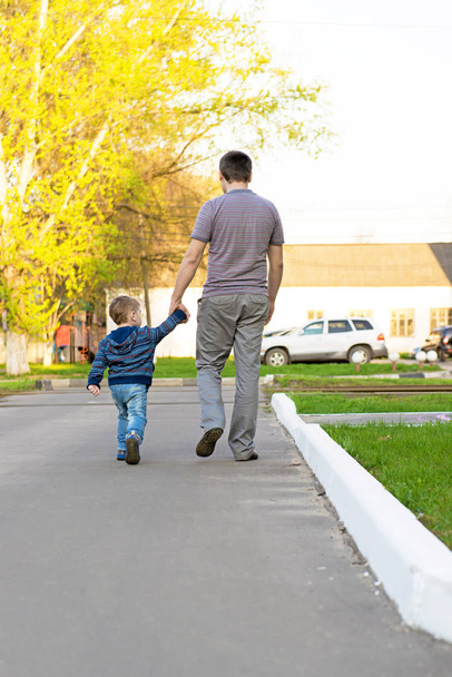 Father and son walking in an urban neighborhood - 写真・画像