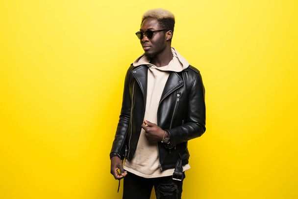 Portrait of a smiling african man in sunglasses in casual clothes isolated over yellow background - Fotó, kép