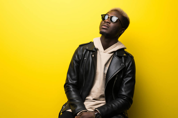 Portrait of a smiling african man in sunglasses in casual clothes isolated over yellow background - Fotó, kép