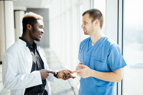 Sekarotuinen Kaksi lääkäriä puhuu, kun he kävelevät modernin sairaalan läpi
 - Valokuva, kuva