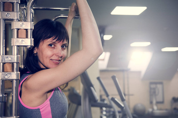 Fitnessübungen, eine Frau führt einen Barbankdruck auf den Schultern durch - Foto, Bild