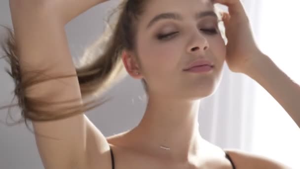 Young beautiful sexy girl in black underwear touches her hair, does her hairstyle, braid, tail, sunlight, near the window, curtain 50 fps - Séquence, vidéo