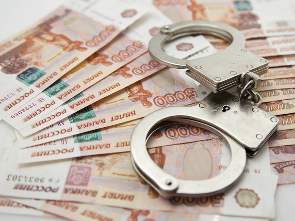 steel handcuffs against the background of the Russian five thousandth banknotes - 写真・画像