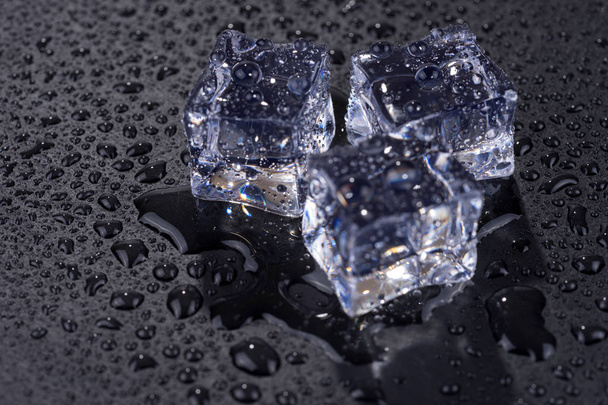 Три кубики льоду з краплями води ізольовані на чорному тлі
 - Фото, зображення