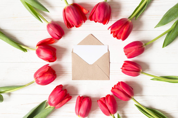 Envelope and frame of red tulips on white wooden background. Mock up. Flat lay with copy space.  - Foto, immagini