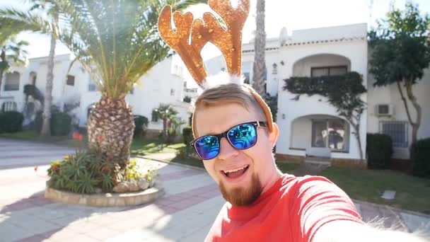 ハッピー クリスマス鹿角 selfie で若い男の笑みを浮かべてします。クリスマス コンセプト - 映像、動画