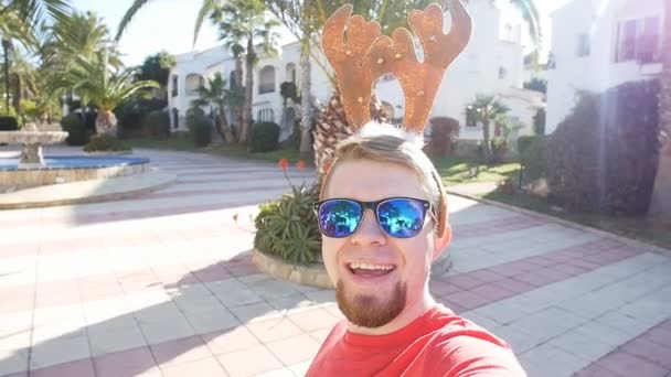 Feliz joven sonriente en Navidad cuernos de ciervo selfie. Concepto de Navidad
 - Imágenes, Vídeo