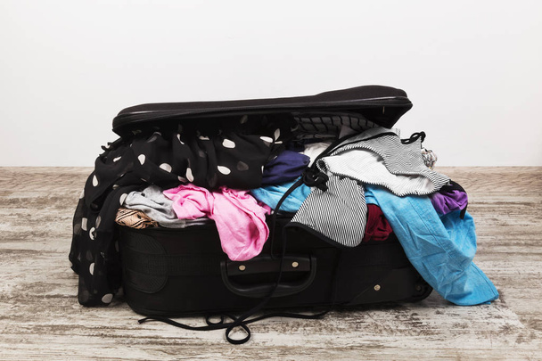 Careless packing of clothes in black suitcase - Foto, imagen