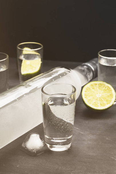 Cold vodka in shot glasses on a black background. Toned - Photo, image