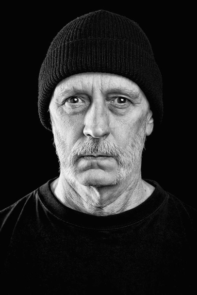 Dramatisches Schwarz-Weiß-Foto eines starken Mannes mit Bart und Wollmütze auf dem Kopf - Foto, Bild