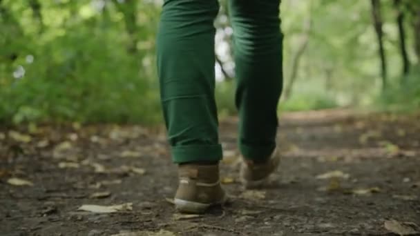 Τα πόδια του μια νεαρή κοπέλα που πηγαίνει μακριά, πράσινο τζιν και αθλητικά παπούτσια - Πλάνα, βίντεο
