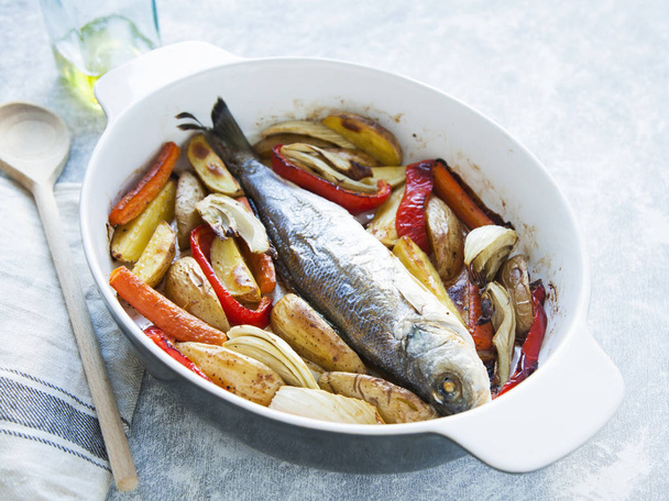Whole sea fish cooked in casserole dish with vegetables (paprika - Foto, afbeelding