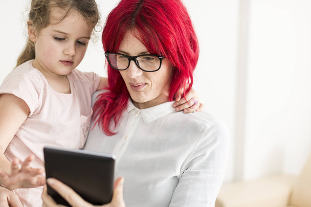 Mom Carrying Child as They Stare at a Tablet Screen Copy Space - Φωτογραφία, εικόνα