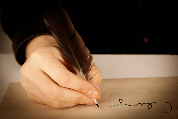 schrijver houdt een vulpen over schrijfpapier en een handtekening - Foto, afbeelding