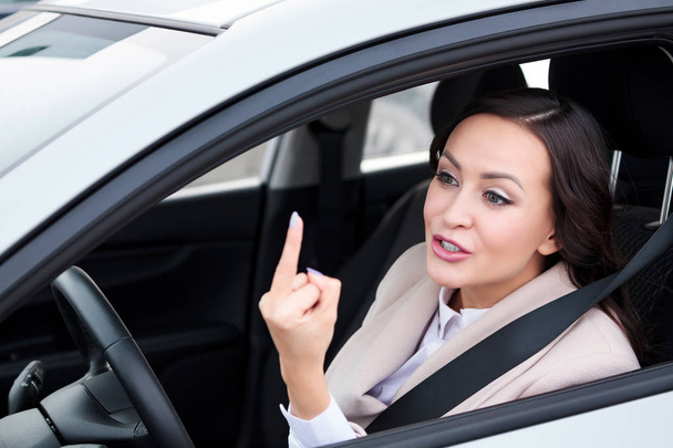 Гарненька жінка водій показує комусь середній палець, поклоніння на дорогах
. - Фото, зображення