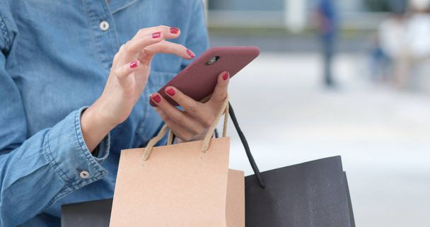 Vrouw met behulp van mobiele telefoon met shopping tassen  - Foto, afbeelding