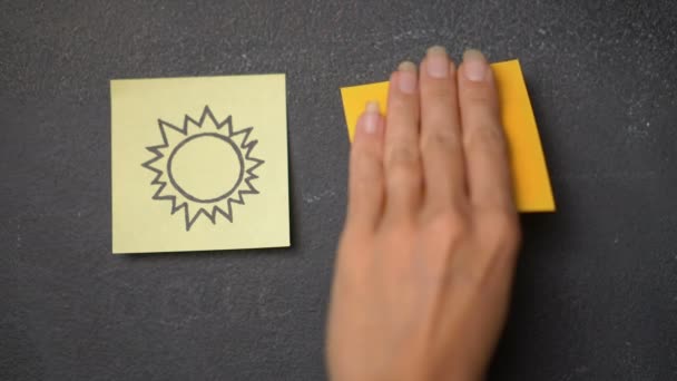 Sticky note on the blackboard / Closeup woman's hand sticking note with happy face icon next to the sun drawing on the blackboard - video in slow motion - Footage, Video