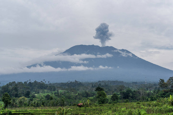 Agung volcano eruption view near rice fields, Bali, Indonesia - 写真・画像