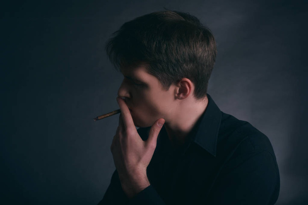 Mann raucht Zigarre. Junge raucht Zigarette auf dunklem Hintergrund. - Foto, Bild