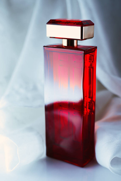  Frasco de perfume rojo sobre fondo claro
 - Foto, imagen