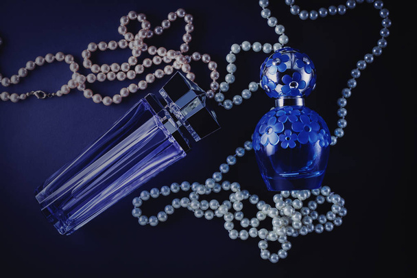 female perfume on a blue background with pearl beads - Photo, Image