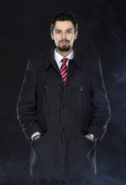 Portrait of fashionable well dressed man with beard posing outdoors looking away, confident and focused mature man in coat standing  on a black background, elegant fashion model. - Fotoğraf, Görsel