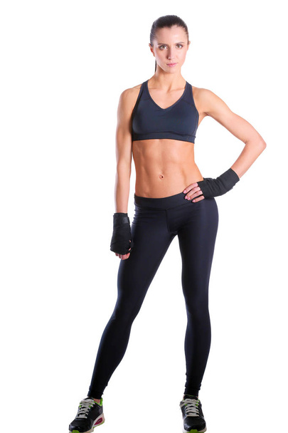 Muscular young woman posing in sportswear against black background. - Фото, зображення