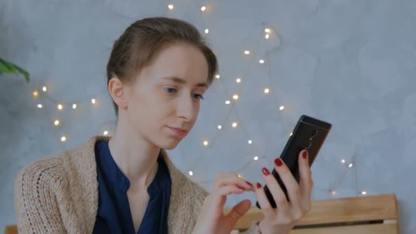 Kobieta korzystająca z pionowego czarny smartfon w domu - Materiał filmowy, wideo