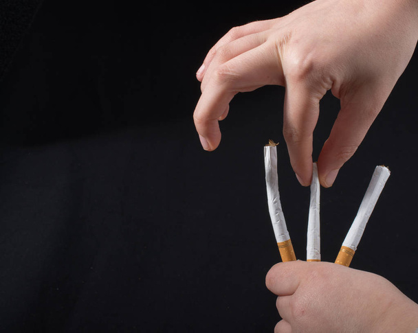 Рука тримає сигарети на чорному тлі
 - Фото, зображення